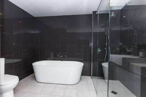 a bathroom with a tub and a toilet and a shower at Trendy, Self Contained Inner City Apartment!! in Wagga Wagga