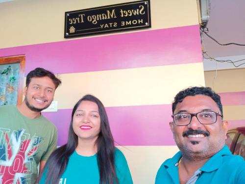 a group of three people standing in front of a wall at Sweet Mango Tree Homestay in Port Blair