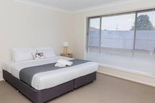 a white bedroom with a large bed and a large window at Lovely 3 Bed, 2 Bath in the City Centre! in Wagga Wagga