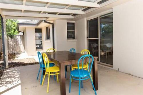 a wooden table and chairs with yellow and blue chairs at Lovely 3 Bed, 2 Bath in the City Centre! in Wagga Wagga