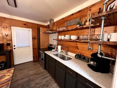 a kitchen with wooden walls and a sink and a door at The Horse Cabin at Natural State Cabins in Morning Star