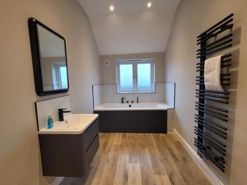 ein Badezimmer mit einer Badewanne, einem Waschbecken und einem Spiegel in der Unterkunft Eastgate Barn, Ashlin Farm Barns in Lincoln