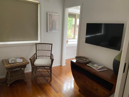 a living room with a tv and a chair and a table at The Delightful Tee House - Kilmore in Kilmore