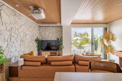 a living room with a brown couch and a stone wall at Chic beachside getaway 2BR 2Bath Fully Equipped in Gold Coast