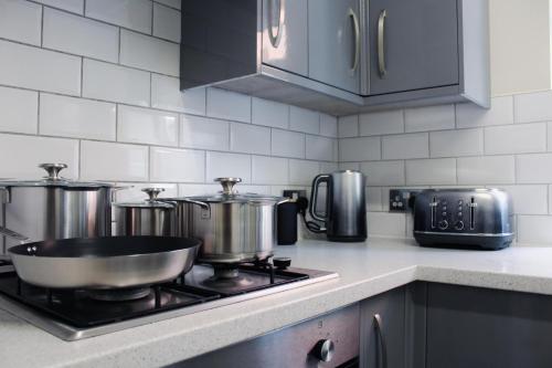 a kitchen with a stove with pots and pans at Victoria Cottage in Cannock