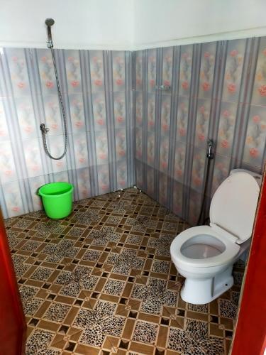 a bathroom with a toilet and a green bucket at Bellarizki Resort in Seleman