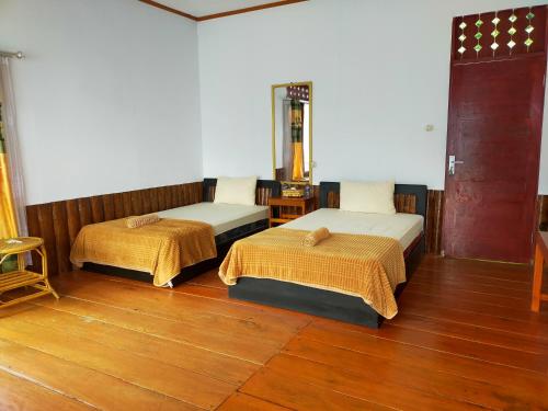 two beds in a room with wooden floors at Bellarizki Resort in Seleman