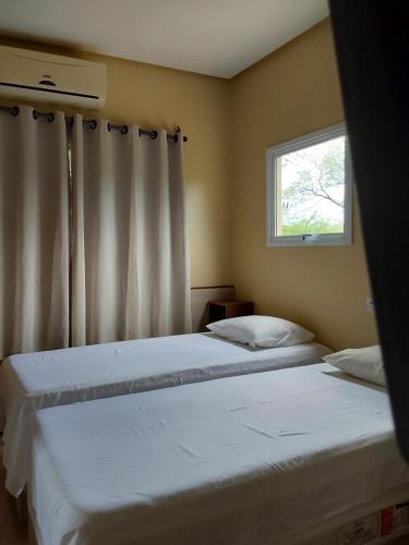 two beds in a bedroom with a window at Casa de temporada Petrolina-PE in Petrolina