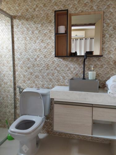 a bathroom with a toilet and a sink and a mirror at Chácara aconchego do Valle in Petrolina