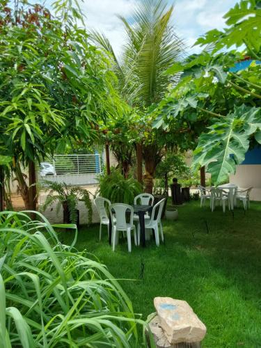 a yard with chairs and a table and trees at Casa de temporada Petrolina-PE in Petrolina