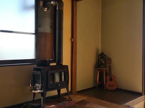 una estufa en la esquina de una habitación con una guitarra en Umi no Mieru Ie Ocean View, en Nishinoomote