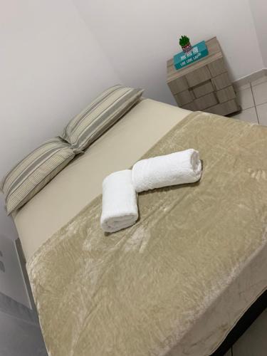 a bed with two rolled towels on top of it at A dois passos do mar… in Vila Velha