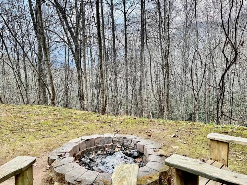 a fire pit in the middle of a field with two benches at Good Life Cabin 1 in Bryson City