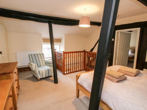 a bedroom with a four poster bed and a chair at Bicton Cottage in Acton