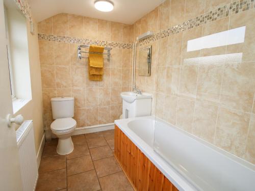 een badkamer met een bad, een toilet en een wastafel bij Bicton Cottage in Acton