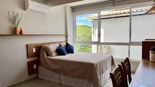 Un dormitorio con una cama con almohadas azules y una ventana en Flat Absolute 6A, en Morro de São Paulo