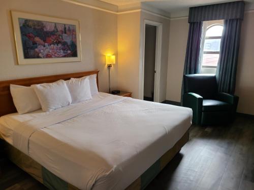 La Quinta Inn by Wyndham Farmington في فارمينغتون: غرفة فندقية بسرير كبير وكرسي