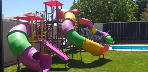 einen Spielplatz mit einer bunten Rutsche im Gras in der Unterkunft Complejo Villa Maria in Ciudad Lujan de Cuyo