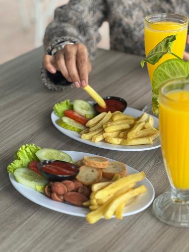 two plates of food on a table with two glasses of orange juice at Hotel Nature Bromo and Resort in Pasuruan