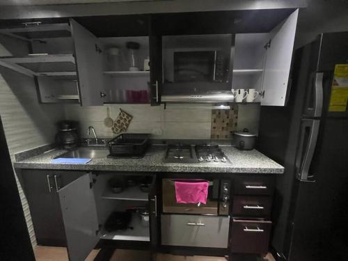 a small kitchen with a stove and a sink at Acogedor Apto Sector Tintal in Bogotá