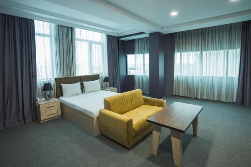 - une chambre avec un lit, une chaise et des fenêtres dans l'établissement Ogguesto Hotel, à Baku
