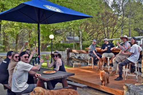 a group of people sitting at a picnic table with an umbrella at Harrietville Hotel Motel in Harrietville