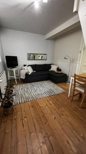 a living room with a black couch and a wooden floor at Apartment Wanha Kartano in Kokkola