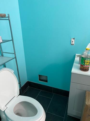 uma casa de banho com um WC e uma parede azul em Private quiet room with shared Bathroom,kitchen,living and dining area em Clinton
