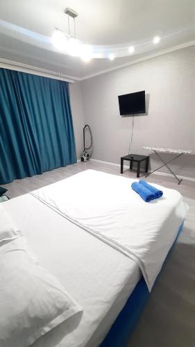 a large white bed in a room with a flat screen tv at Жк ривьера in Kokshetau