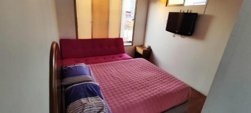 uma pequena cama vermelha num quarto com uma televisão em Casa de Verano em Iquique