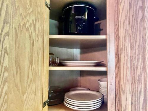 a cupboard with plates and a coffee pot and plates at Good Life Cabin 2 in Bryson City