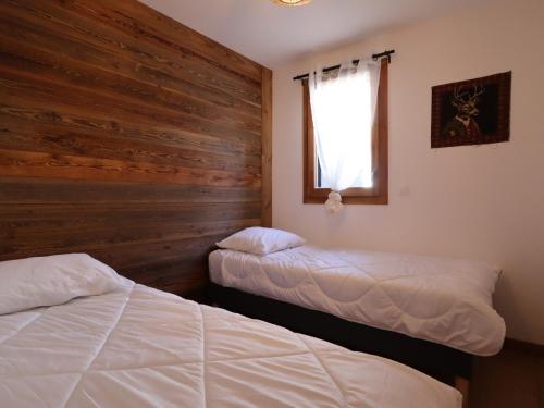 - une chambre avec 2 lits et un mur en bois dans l'établissement Appartement raffiné en plein centre avec 3 chambres, balcon, terrasse, parking et wifi - FR-1-623-334, aux Gets