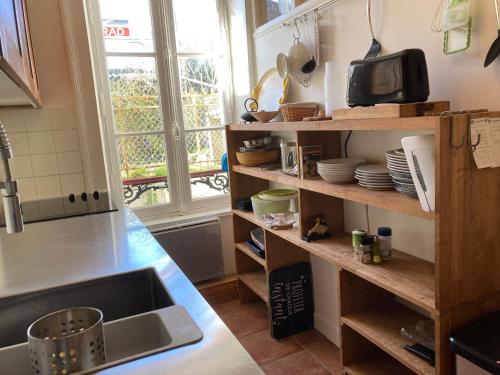 - une cuisine avec un évier et une étagère avec de la vaisselle dans l'établissement Appartement élégant 3* au coeur de Le Palais, 2 chambres, proche commerces et plage - FR-1-418-197, au Palais