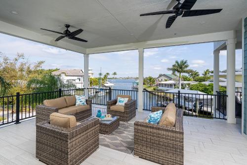 a patio with chairs and tables and a view of the water at Magnificent New Build Private Pool Home on the North Tip of Fort Myers Beach! home in Fort Myers Beach