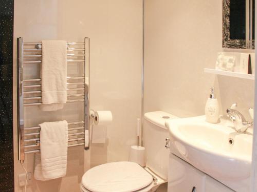a white bathroom with a toilet and a sink at The Beehive in Mundesley