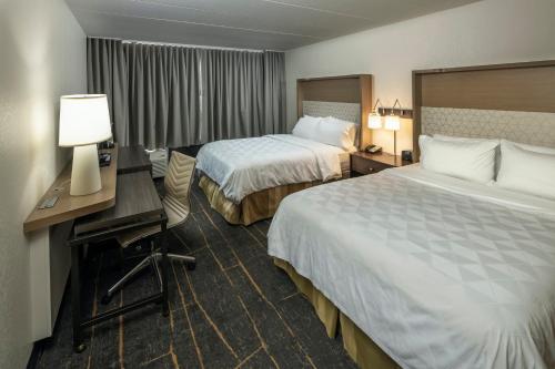 a hotel room with two beds and a desk at Holiday Inn Detroit Lakes by IHG in Detroit Lakes