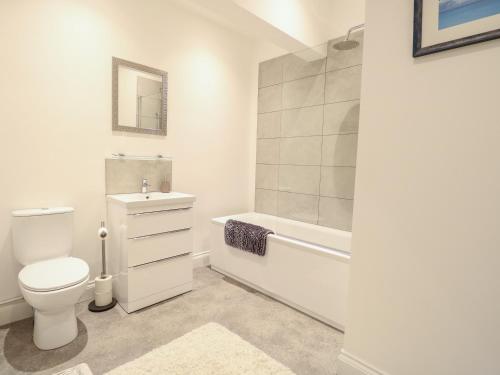 een witte badkamer met een toilet en een bad bij Apartment 7 in Lowestoft