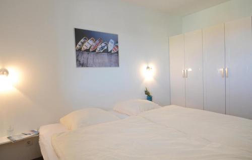 a white bedroom with a bed and a painting on the wall at Appartement Seestern B in Schönhagen