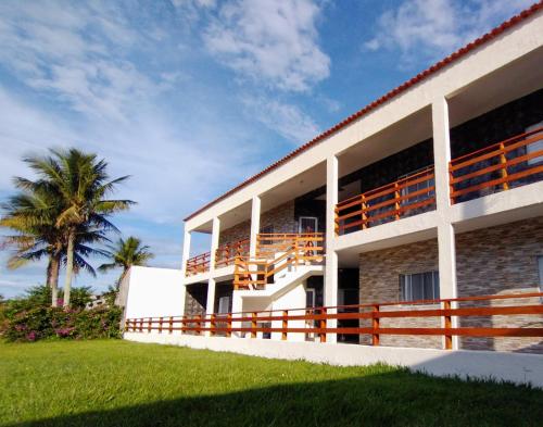 budynek z palmą przed nim w obiekcie Recanto da Lagoa Flat w mieście Ilha Comprida