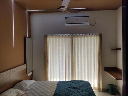 a bedroom with a bed and a window with a fan at Eva Meadows in Kollam