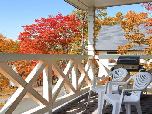 a porch with two white chairs and a grill at Resort Villa Takayama in Takayama