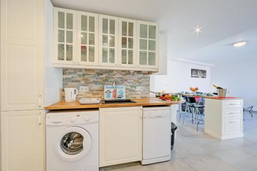 une cuisine avec des armoires blanches et une laveuse et une sécheuse dans l'établissement Le Bristol V - Happy Rentals, à Juan-les-Pins