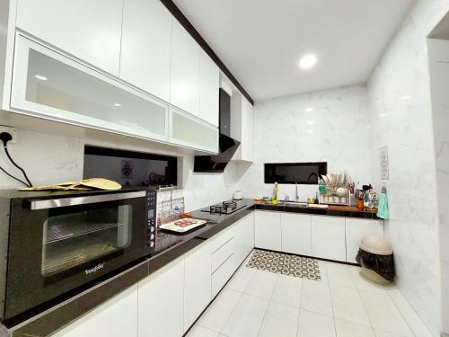 een keuken met witte kasten en een zwarte oven bij Good2Stay Villa in Melaka