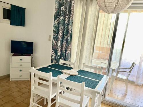 une table et des chaises dans une pièce avec une fenêtre dans l'établissement Studio cabine avec terrasse, 4 couchages, parking privé - Marseillan - FR-1-326-415, à Marseillan