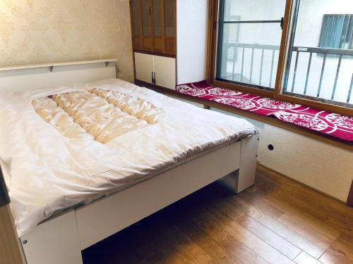 a white bed in a room with two windows at 日久の宿 in Kokubunji