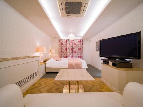 HOTEL U's Kouroen - Vacation STAY 11243v في نيشينومايا: غرفة صغيرة بها سرير وتلفزيون بشاشة مسطحة