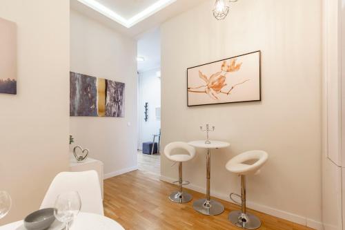 um quarto branco com dois bancos e uma mesa em Luxury Quentin Apartment 3 BEDRM, 2 BATHRM em Budapeste