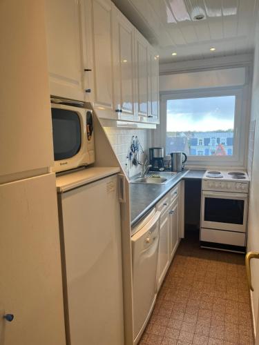 une cuisine avec des armoires blanches et un micro-ondes dans l'établissement Appt plein centre , face mer avec parking, à Le Touquet-Paris-Plage