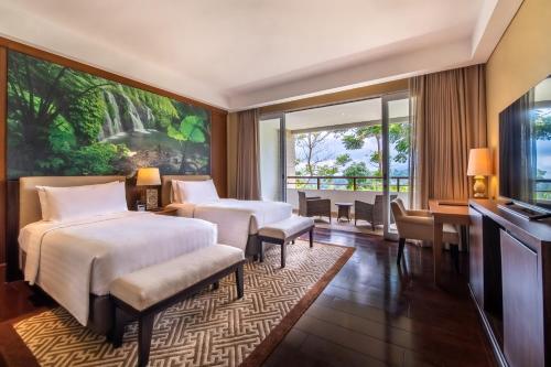 a bedroom with two beds and a desk and a window at HOMM Saranam Baturiti, Bali in Bedugul