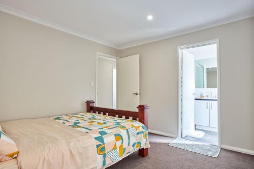 een witte slaapkamer met een bed en een spiegel bij Gorgeous Family House near Shops in Perth